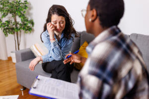 An adult female therapist is conducting a therapy and anxiety counseling session with a female patient.